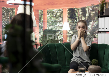 Troubled teen expressing her anxiety and mental health issues during a therapy session with psychologist, low confidence and internal frustration. Scared confused girl with personal troubles. 124797065