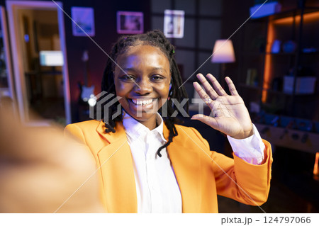 Portrait of ecstatic teenager filming content for online streaming channel in apartment studio, entertaining fans. Gen z influencer at home interacting with subscribers, doing greeting hand gesture 124797066