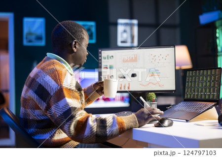 Research specialist reviewing financial elements and expenses to create strategic report for revenue growth. African american financier examines capital funds balance, remote work. Research specialist reviewing financial elements and expenses to create strategic report for revenue growth. African american financier examines capital funds balance, remote work. 124797103