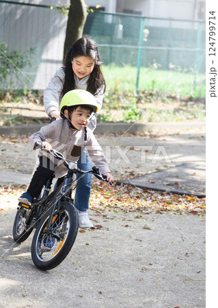 自転車の練習をする弟のお手伝いをする姉 124799714