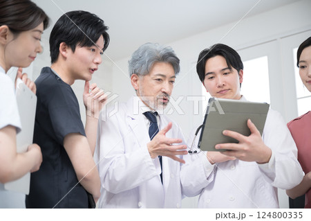 カルテや診察などの状況を確認するチーム医療の医師たち、 指導医と研修医のイメージ 124800335