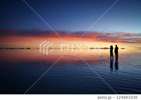 ポリビアウユニ塩湖の夕日を見るカップル 124801030