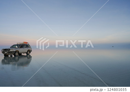 ウユニ塩湖の朝焼けを走る車 124801035