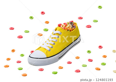 A bright yellow sneaker filled with colorful cereal, isolated on white 124801193
