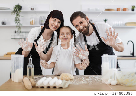 Happy Caucasian family enjoying time together in modern kitchen cooking and playing with flour. Parents and young daughter engaging in baking activity, showing cheerful expressions Happy Caucasian family enjoying time together in modern kitchen cooking and playing with flour. Parents and young daughter engaging in baking activity, showing cheerful expressions 124801389