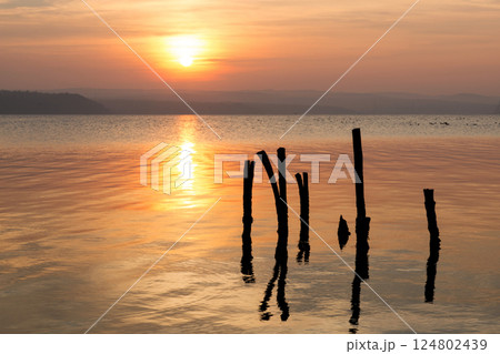 Dramatic golden sunset over a lake with beautiful reflections and silhouettes. Selctive focus. Copy space. 124802439