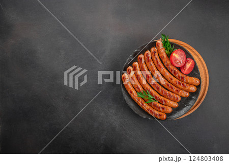 Grilled sausages with tomato on dark background, top view, copy space 124803408