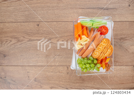 balanced lunch box with fresh fruits, vegetables, meat, and nuts on a wooden background, top view. copy space balanced lunch box with fresh fruits, vegetables, meat, and nuts on a wooden background, top view. copy space 124803434