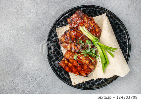 A grilled pork ribs Barbecue on plate on a light background, top view. copy space A grilled pork ribs Barbecue on plate on a light background, top view. copy space 124803709