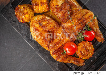 Fried chicken with fresh herbs. Tobacco chicken on a dark background. Georgian dish. top view. copy space. 124803738