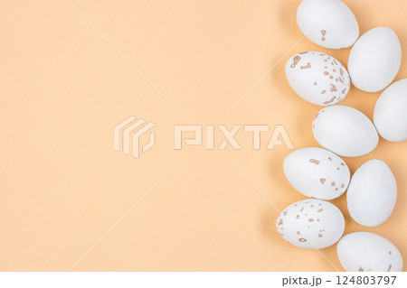 Minimalist Easter flat lay featuring elegant decorations speckled eggs. Composition in shape of Easter white egg on yellow background for creative designs Minimalist Easter flat lay featuring elegant decorations speckled eggs. Composition in shape of Easter white egg on yellow background for creative designs 124803797