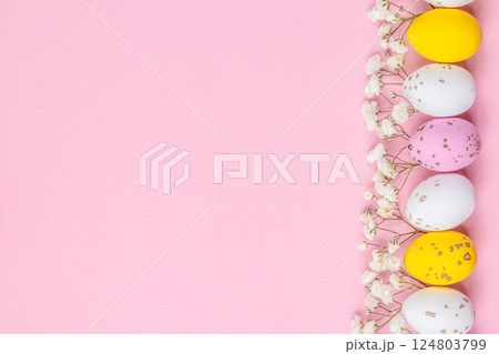 Festive Easter background. Easter eggs and flowers on a pink table. Card with a place for text. Top view 124803799