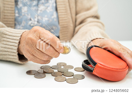 Asian senior or elderly old lady woman holding counting coin money in purse. Poverty, saving problem in retirement. Asian senior or elderly old lady woman holding counting coin money in purse. Poverty, saving problem in retirement. 124805602