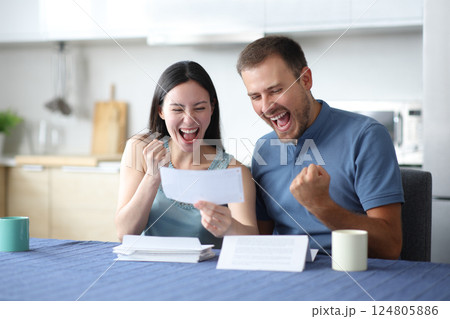 Excited interracial couple reading good news on letter Excited interracial couple reading good news on letter 124805886