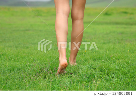 Bare woman legs walking on the grass in nature Bare woman legs walking on the grass in nature 124805891