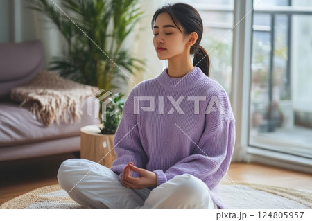 Woman meditating in the living room. 124805957