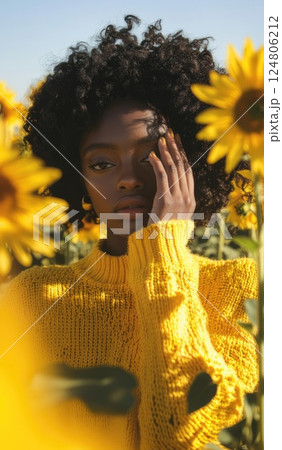 A close up of a person wearing a yellow sweater with their hand on their face. 124806212