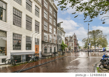 A picturesque view of a charming street in Amsterdam showcasing beautiful historic buildings, lively atmosphere, and bicycles parked along the pavement. A picturesque view of a charming street in Amsterdam showcasing beautiful historic buildings, lively atmosphere, and bicycles parked along the pavement. 124806818