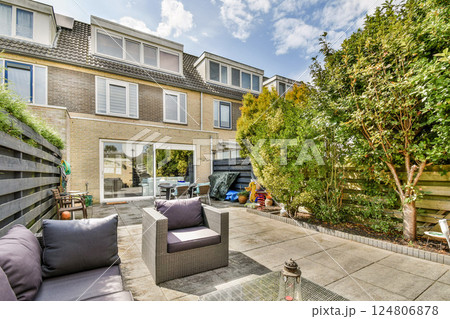 A beautifully arranged outdoor patio surrounded by lush greenery, featuring comfortable seating and decorative plants, creating a serene retreat atmosphere. 124806878