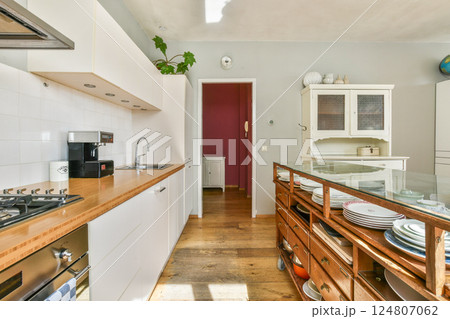 A contemporary kitchen featuring sleek cabinetry, a wooden countertop, and a warm color palette. The space is designed for functionality and style. 124807062