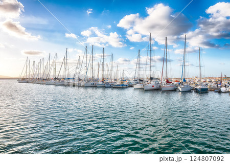 Unbelivable summer view of the Alghero Marina yacht port at the Gulf of Alghero with anchored sailboats. Unbelivable summer view of the Alghero Marina yacht port at the Gulf of Alghero with anchored sailboats. 124807092
