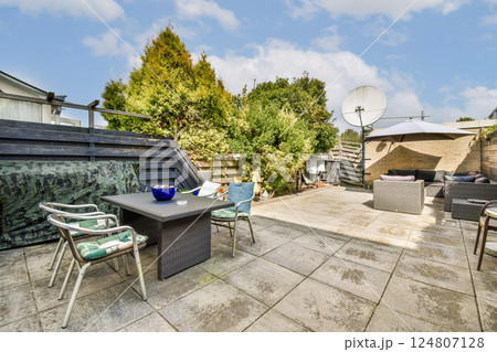 An inviting outdoor patio space featuring modern furniture and greenery, perfect for relaxation or gatherings in a serene environment. 124807128