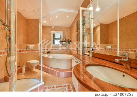 A stylish modern bathroom featuring a large bathtub, a well-designed vanity, and soft lighting creating an inviting atmosphere. 124807258