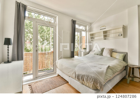 Bright and inviting bedroom featuring large windows, a soft bed, and minimalistic decor, creating a serene atmosphere for relaxation and comfort. Bright and inviting bedroom featuring large windows, a soft bed, and minimalistic decor, creating a serene atmosphere for relaxation and comfort. 124807286