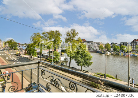 This image showcases a picturesque urban landscape featuring a waterway bordered by lush trees, under a clear blue sky. It merges nature and architecture beautifully. This image showcases a picturesque urban landscape featuring a waterway bordered by lush trees, under a clear blue sky. It merges nature and architecture beautifully. 124807336