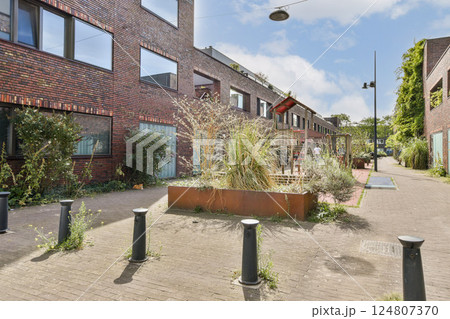 A vibrant urban scene featuring modern brick buildings interspersed with lush green plants. The area is designed for both aesthetics and functionality. A vibrant urban scene featuring modern brick buildings interspersed with lush green plants. The area is designed for both aesthetics and functionality. 124807370