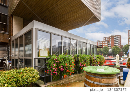 A contemporary structure features large glass windows and vibrant greenery, blending nature with architecture in an urban setting. 124807375