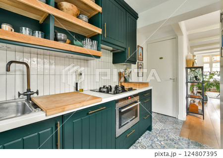 Modern kitchen design featuring green cabinetry, wooden shelves, and stylish accessories, blending functionality with aesthetic appeal. Modern kitchen design featuring green cabinetry, wooden shelves, and stylish accessories, blending functionality with aesthetic appeal. 124807395