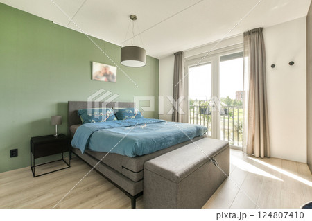 A sleek and inviting bedroom featuring a comfortable bed, stylish decor, and ample natural light, creating a tranquil atmosphere for relaxation. 124807410