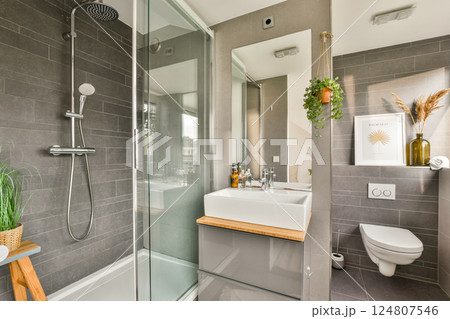 A sleek, contemporary bathroom featuring a shower, sink, and tasteful decor. The integration of plants adds a refreshing touch to the minimalistic design. A sleek, contemporary bathroom featuring a shower, sink, and tasteful decor. The integration of plants adds a refreshing touch to the minimalistic design. 124807546