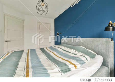 Elegant modern bedroom featuring a cozy bed with striped bedding, minimalist decor, and a stylish light fixture, creating a serene atmosphere. Elegant modern bedroom featuring a cozy bed with striped bedding, minimalist decor, and a stylish light fixture, creating a serene atmosphere. 124807553