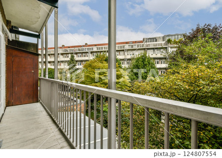 A serene modern balcony offering a view of lush trees and contemporary architecture in the distance. Perfect for relaxation and enjoying nature. A serene modern balcony offering a view of lush trees and contemporary architecture in the distance. Perfect for relaxation and enjoying nature. 124807554