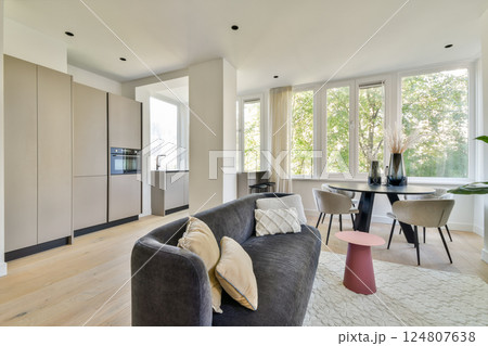 Bright and airy modern living room featuring large windows, sleek furniture, and a cozy atmosphere filled with natural elements. A perfect blend of comfort and style. 124807638