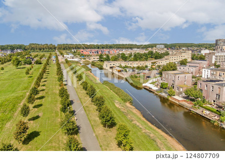A beautifully captured aerial view showcasing a vibrant urban landscape featuring a winding waterway, lush greenery, and modern buildings along the shore. A beautifully captured aerial view showcasing a vibrant urban landscape featuring a winding waterway, lush greenery, and modern buildings along the shore. 124807709