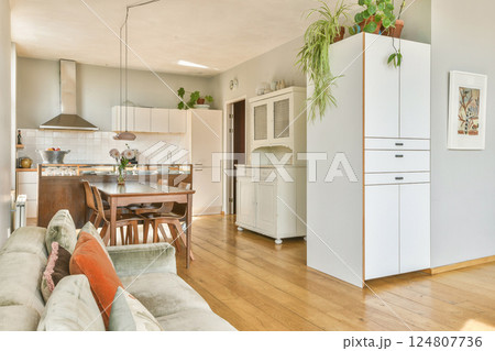 A stylish kitchen featuring light wood flooring, white cabinetry, abundant natural light, and a welcoming dining area, creating a warm and inviting ambiance. 124807736
