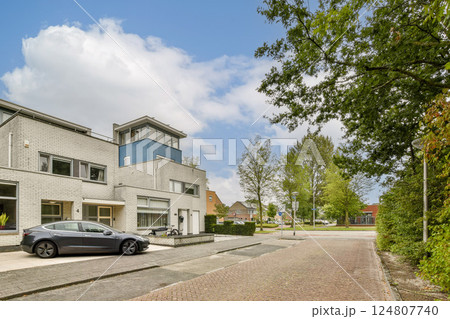 A contemporary residential structure featuring large windows, surrounded by greenery and showcasing a clear blue sky with clouds. A contemporary residential structure featuring large windows, surrounded by greenery and showcasing a clear blue sky with clouds. 124807740