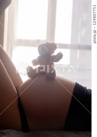 Pregnant Woman with toy Bear on Belly 124807751