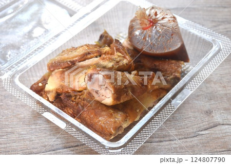 roasted chop chicken meat wing and leg dipping with spicy sauce in transparent plastic packaging on table 124807790