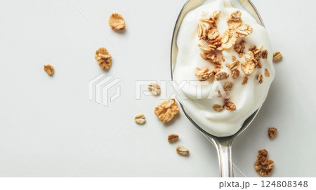 A spoonful of creamy yogurt topped with crunchy cereal flakes is beautifully arranged on a minimal light background 124808348