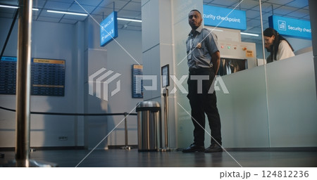 Airline Captain and Two Stewardesses Walking, Passing by TSA Worker at Security Checkpoint 124812236