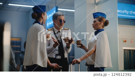 Crowded Airport Terminal: Airline Captain and Two Beautiful Stewardesses Talking, Waiting for Flight Crowded Airport Terminal: Airline Captain and Two Beautiful Stewardesses Talking, Waiting for Flight 124812392