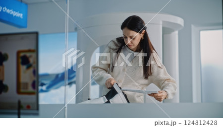Woman with Carry-On Baggage During Screening. Computer Screen with X-ray Images of Luggage 124812428