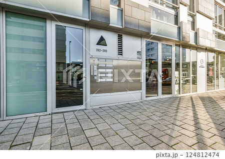 Showcases a contemporary building featuring a sleek glass facade and geometric shapes, reflecting urban life and modern design aesthetics. 124812474