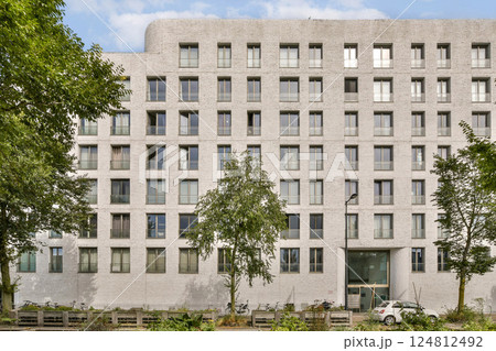 A striking modern building showcasing concrete and glass elements, framed by greenery. The design emphasizes transparency and urban living. A striking modern building showcasing concrete and glass elements, framed by greenery. The design emphasizes transparency and urban living. 124812492
