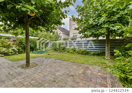 A serene garden scene showcasing lush greenery, well-maintained trees, and a paved pathway, perfect for relaxation or outdoor activities. A serene garden scene showcasing lush greenery, well-maintained trees, and a paved pathway, perfect for relaxation or outdoor activities. 124812534