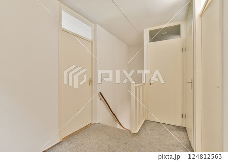 Bright and airy hallway showcasing a minimalist design with white walls and doors, accented by a subtle staircase. The clean lines create a sleek ambiance. Bright and airy hallway showcasing a minimalist design with white walls and doors, accented by a subtle staircase. The clean lines create a sleek ambiance. 124812563